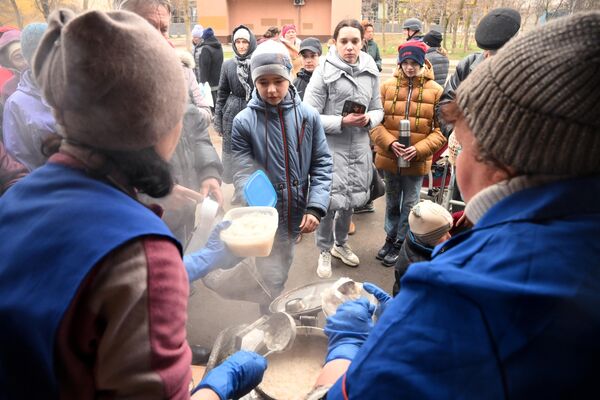 Localnici stau în rând după mâncare caldă în centrul de ajutor umanitar din sectorul Levoberejie al Mariupolului. - Sputnik Moldova-România