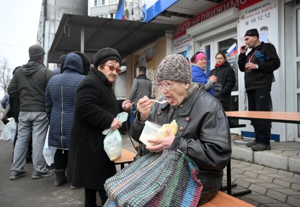 O localnică mănâncă terci în fața centrului de ajutor umanitar din sectorul Levoberejie al Mariupolului. - Sputnik Moldova-România