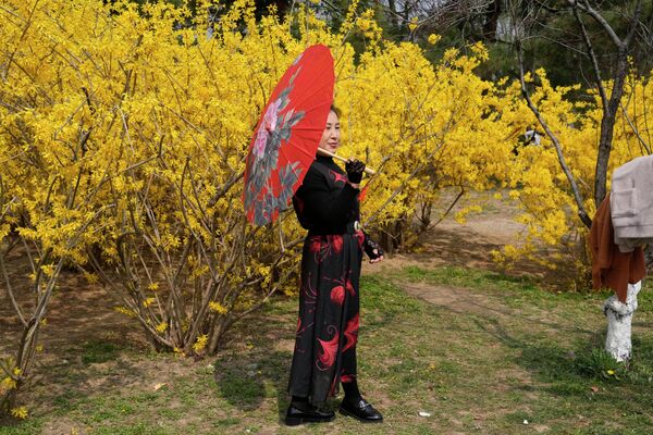 Женщина позирует рядом с цветами в пекинском парке. - Sputnik Молдова