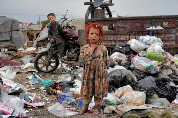 Doi copii afgani stau printre grămezi de gunoi lângă casa lor, în Kabul, Afganistan - Sputnik Moldova