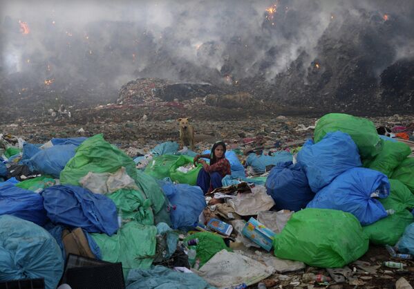 Старьевщица сортирует вещи во время пожара на свалке Бхалсва в Нью-Дели, Индия. - Sputnik Молдова