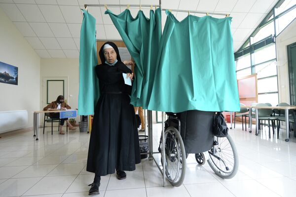 Сестра-бенедиктинка из аббатства Сент-Сесиль готовится отдать свой голос во время второго тура президентских выборов во Франции на избирательном участке в Солеме. - Sputnik Молдова