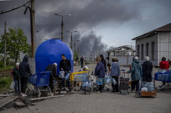 Localnici care stau în rând să ia apă potabilă pe una dintre străzile Mariupolului. - Sputnik Moldova