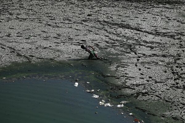 Мальчик идет по пересохшему руслу реки Ямуна в жаркий день в Нью-Дели, Индия - Sputnik Молдова