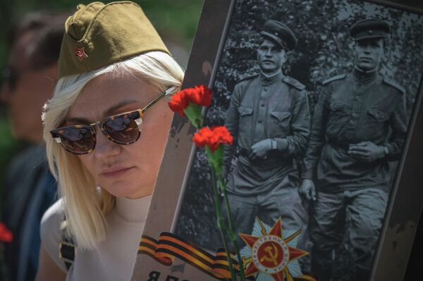 O femeie ține în mână o fotografie cu soldații din Al Doilea Război Mondial în timpul marșului Regimentului Nemuritor la Cimitirul Eliberatorilor Belgradului, din Belgrad, pe 9 mai 2022.  - Sputnik Moldova-România