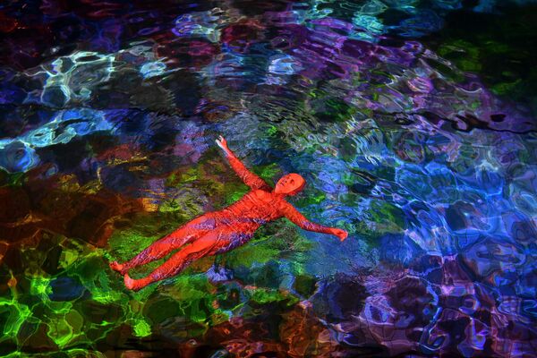 Женщина плавает в подсвеченной воде крытого бассейна Hirschengraben в Берне во время художественного акции швейцарского художника Пипилотти Риста  в поддержку сохранения кораллов. - Sputnik Молдова