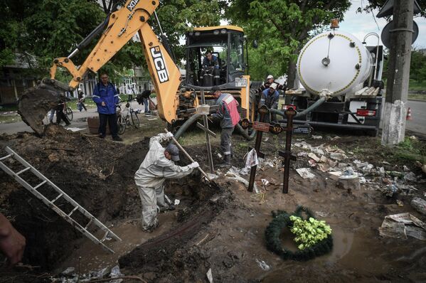 Сотрудники коммунальной службы эксгумируют тела погибших местных жителей в связи с прорывом водопровода в месте захоронения - Sputnik Молдова