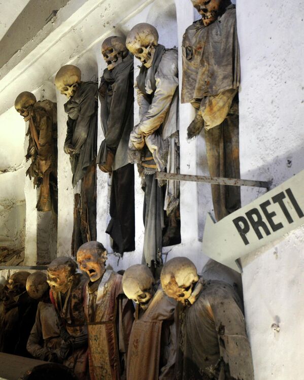 Această fotografie este realizată pe 2 octombrie 2009. În imagine sunt prezentate cadavrele mumificate, iar pe panou este scris „călugări”. Lucrarea este expusă în Catacombele Capucinilor din Palermo, Italia - Sputnik Moldova