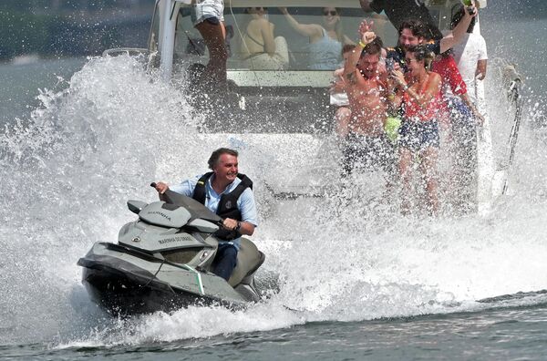 Президент Бразилии Жаир Болсонару брызгает на людей, участвующих в лодочной прогулке по озеру Параноа в Бразилиа, 15 мая 2022 года. - Sputnik Молдова