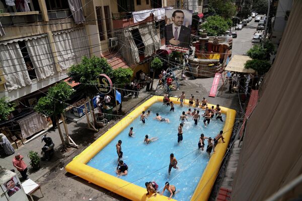 Дети плавают в надувном бассейне, который установили сторонники бывшего премьер-министра Саада Харири, чтобы продемонстрировать свое намерение бойкотировать парламентские выборы, в Бейруте, Ливан, в воскресенье, 15 мая 2022 года. - Sputnik Молдова
