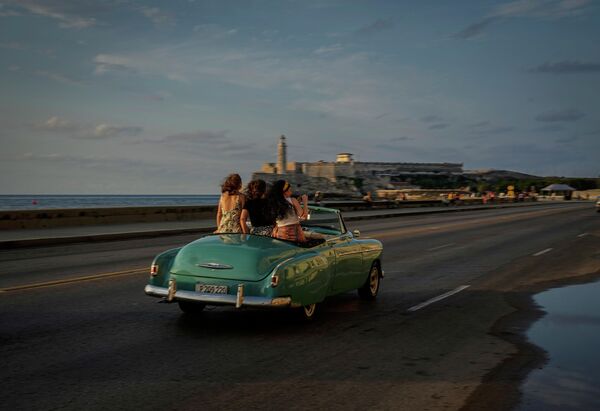 Туристы едут по Малекону на старинном американском автомобиле в Гаване, Куба, понедельник, 16 мая 2022 года. Администрация Байдена объявила, что расширит количество рейсов на Кубу и снимет ограничения эпохи Дональда Трампа на денежные переводы, которые могут отправлять иммигранты. - Sputnik Молдова