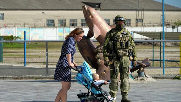 O femeie cu copilul trece pe lângă un soldat rus - Sputnik Moldova
