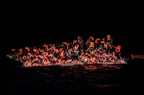 Мигранты падают в воду, из последних сил пытаясь уцепиться за борт перевернутой лодки в водах Туниса. - Sputnik Молдова