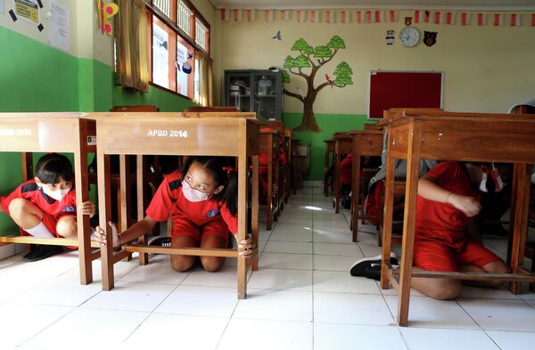 Школьники прячутся под партами во время учений по подготовке к сильным землетрясениям и цунами на Бали, Индонезия. - Sputnik Молдова