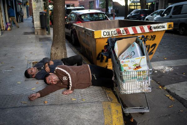 Oamenii se odihnesc pe un trotuar în timp ce fac o pauză de la colectarea materialelor pentru a le vinde. Imaginea a fost făcută în Buenos Aires, Argentina, vineri, 29 aprilie 2022. - Sputnik Moldova