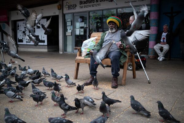 Un bărbat hrănește porumbei în centrul orașului Bradford, în nordul Angliei, pe 24 mai 2022.  - Sputnik Moldova
