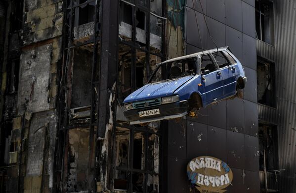 Служба МЧС РФ загружает при помощи крана на трал поврежденный автомобиль в Мариуполе - Sputnik Молдова