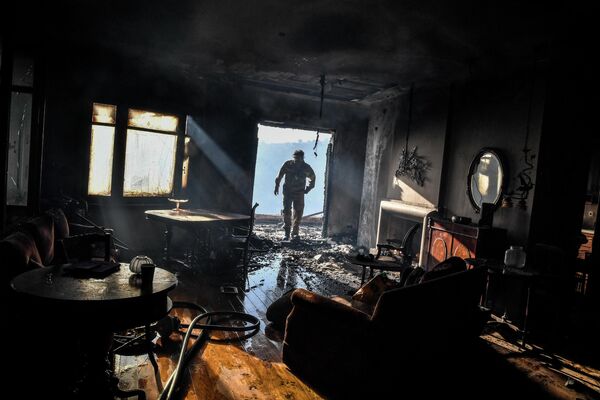 Un pompier se plimbă într-o casă parțial arsă în timpul unui incendiu din zona Panorama Voulas, la sud de Atena, pe 4 iunie 2022 Un incendiu alimentat de vânturi puternice a aprins vegetația într-o suburbie de sud a Atenei, a declarat pompierii, forțând locuitorii să se evacueze. - Sputnik Moldova-România