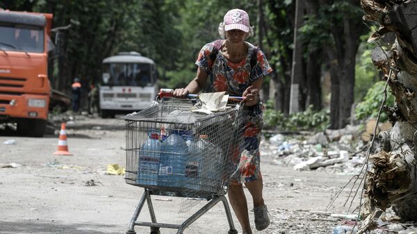 Женщина катит тележку с водой на одной из улиц в Мариуполе - Sputnik Молдова