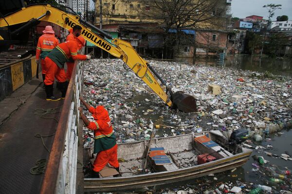 Городские рабочие убирают мусор, плавающий на реке Негро, уровень воды в которой поднялся из-за дождя, в Манаусе, Бразилия. - Sputnik Молдова