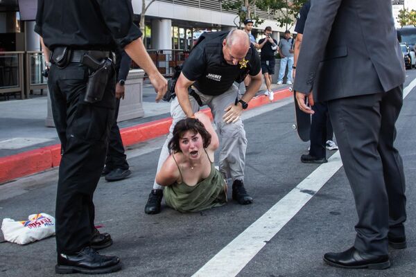 Офицер секретной службы полиции задерживает протестующую, выбежавшую к кортежу лидеров Северной и Южной Америки, направляющихся на Саммит Америк в Лос-Анджелесе. - Sputnik Молдова