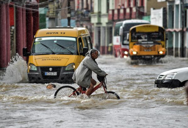 Мужчина едет на велосипеде по затопленной улице Гаваны. - Sputnik Молдова