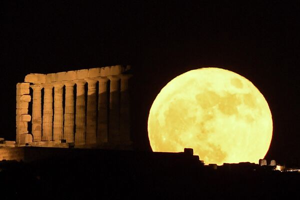 Această fotografie prezintă Lună plină, cunoscută sub numele de „Luna de căpșuni”, care apare în spatele Templului lui Poseidon de la Capul Sunion situat la sud de Atena, pe 14 iunie 2022. - Sputnik Moldova-România