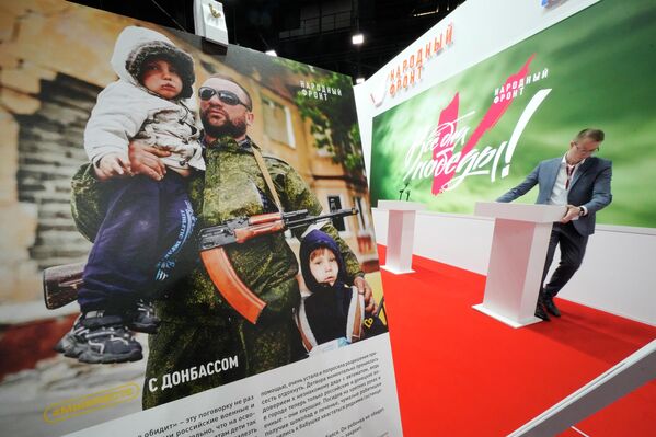 Un bărbat instalează o tribună la un stand al mișcării Frontului Popular Rus, iar în afiș se arată un militar din Donbas cu doi copii. Imaginea a fost surprinsă la Forumul Economic Internațional 2022 desfășurat la Sankt Petersburg - Sputnik Moldova