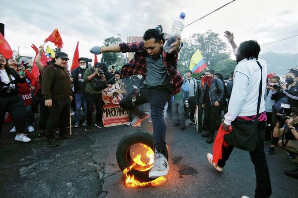 Студент университета прыгает через горящую покрышку во время демонстрации против правительства президента Гильермо Лассо в рамках начавшихся накануне протестов коренных народов в центре Кито 14 июня 2022 года.  - Sputnik Молдова