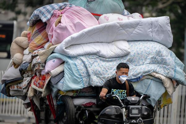 Мужчина в маске едет на тележке с постельным бельем и тканями по улице в Пекине, четверг, 16 июня 2022 года. - Sputnik Молдова