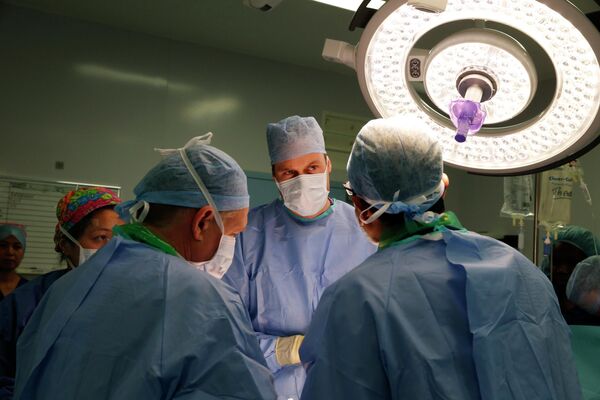 Prințul William al Marii Britanii, în centru, Ducele de Cambridge, Președintele Fundației Royal Marsden NHS (National Health Service) Foundation Trust, îl ascultă pe chirurgul șef Pardeep Kumar, în dreapta, în timp ce urmărește o intervenție chirurgicală pentru îndepărtarea unei tumori a vezicii urinare la un pacient de sex masculin în timpul vizitei la spitalul Royal Marsden din Chelsea din Londra, joi, 7 noiembrie 2013. - Sputnik Moldova