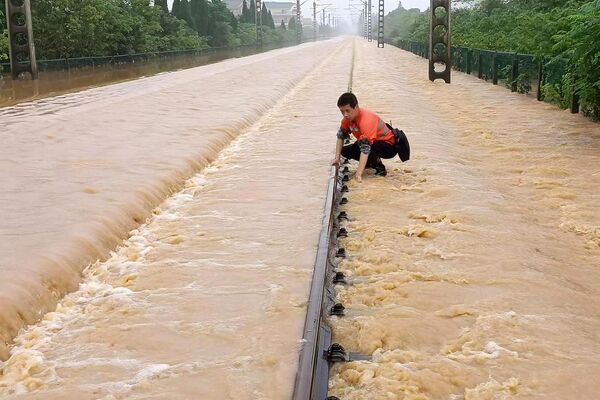 Сотрудник железной дороги проверяет затопленный железнодорожный путь после проливных дождей в Китае. - Sputnik Молдова