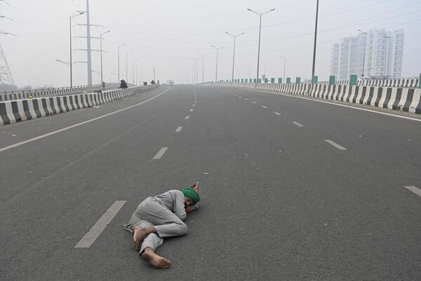 Индийский фермер заснул на пустынной дороге, перекрытой из-за забастовки аграриев. - Sputnik Молдова