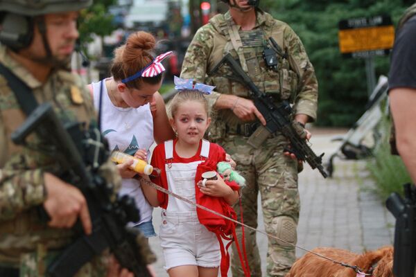Сотрудники правоохранительных органов сопровождают семью с места стрельбы на параде четвертого июля в Хайленд-парке, штат Иллинойс, США. - Sputnik Молдова