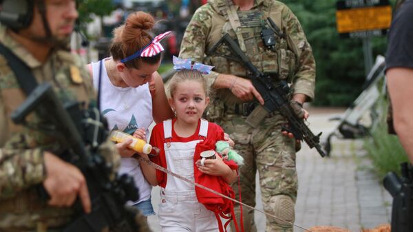  Сотрудники правоохранительных органов сопровождают семью с места стрельбы на параде Четвертого июля в Хайленд-парке, штат Иллинойс, США - Sputnik Молдова