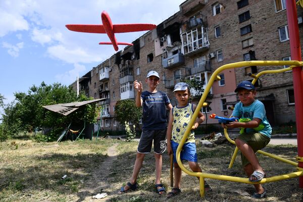 Copiii se joacă pe terenul de joacă aflat în curtea unui bloc de locuit din orașul Volnovaha - Sputnik Moldova