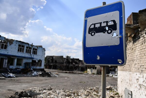 Un semn de circulație plasat într-o stație de autobuz, situat lângă un bloc distrus din orașul Volnovaha - Sputnik Moldova
