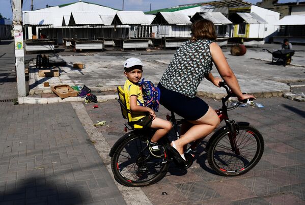 O femeie și un copil se plimbă cu bicicleta pe o stradă din orașul Volnovaha - Sputnik Moldova