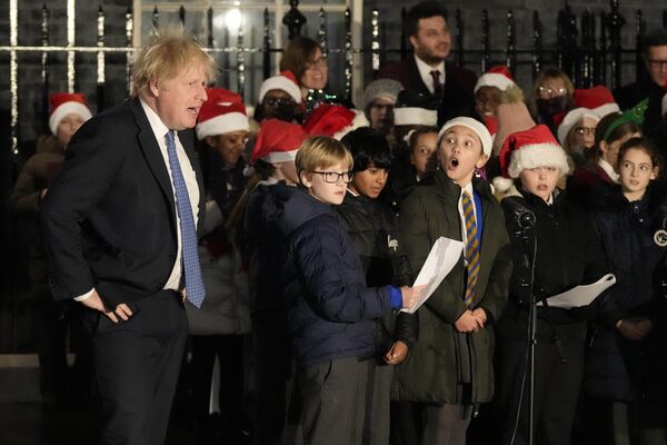 Премьер-министр Великобритании Борис Джонсон подпевает детскому хору во время церемонии включения огней рождественской елки на Даунинг-стрит в Лондоне 1 декабря 2021 года. - Sputnik Молдова