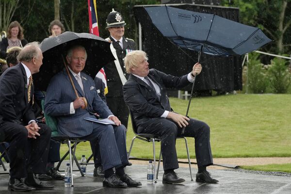 Prințul Charles al Marii Britanii și prim-ministrul Boris Johnson la adăpost de ploaie în timpul inaugurării Memorialului Poliției Marii Britanii la Arboretumul Național din Alrewas din Anglia, 28 iulie 2021 - Sputnik Moldova-România