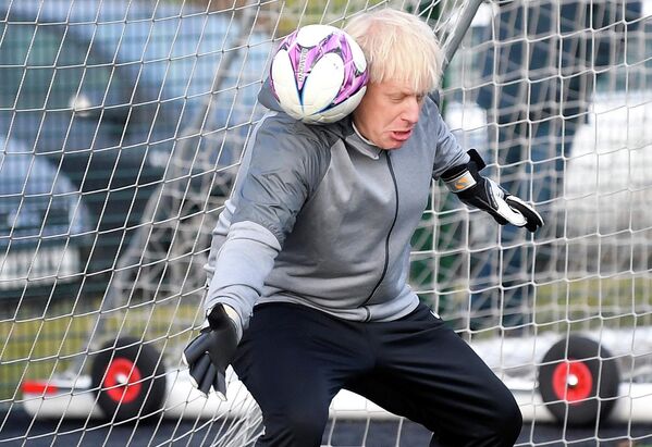 Prim-ministrul britanic Boris Johnson încearcă să se apare de o lovitură cu mingea în timpul exercițiului de încălzire înaintea unui meci de fotbal feminin în Cheadle Hulme, nord-vestul Angliei, în perioada campaniei electorale, 7 decembrie 2019 - Sputnik Moldova-România