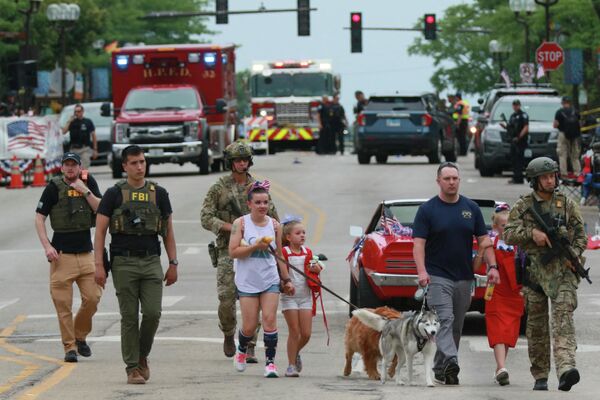 Правоохранительные органы сопровождают семью с места стрельбы на параде 4 июля 2022 года в Хайленд-Парке, штат Иллинойс. - Sputnik Молдова