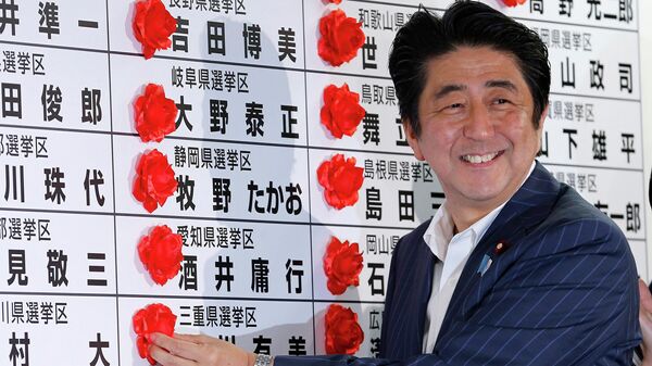 Премьер-министр Японии Синдзо Абэ ставит розетку на имя победившего кандидата от своей Либерально-демократической партии во время подсчета голосов на выборах в верхнюю палату парламента в штаб-квартире партии в Токио - Sputnik Moldova