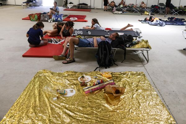 Turiștii așteaptă pe paturi improvizate la parcul de expoziții din La Teste-de-Buch, după ce au fost evacuați din camping din cauza unui incendiu care a izbucnit pe fundul Dunei du Pilat, sud-vestul Franței, pe 13 iulie 2022 - Sputnik Moldova-România