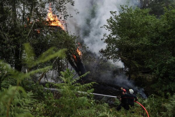 Pompierii lucrează la stingerea unui incendiu la fundul Dunei Pilat, lângă La Teste-de-Buch, sud-vestul Franței, pe 13 iulie 2022. - Un incendiu în curs din după-amiaza zilei de 12 iulie 2022 a ars 1500 de hectare de pădure de pini lângă Landiras (Gironda), la aproximativ 40 de kilometri sud de Bordeaux, ceea ce a dus la evacuarea a 150 de persoane, a spus prefectura. - Sputnik Moldova-România