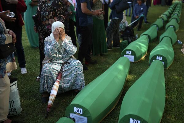 Боснийская мусульманка Бахта Алджич скорбит рядом с гробом с останками ее мужа, который входит в число 50 недавно идентифицированных жертв геноцида в Сребренице в Потокари, понедельник, 11 июля 2022 г.  - Sputnik Молдова