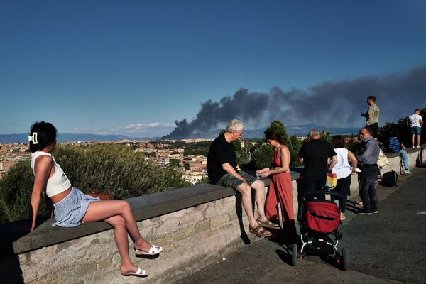 Люди на площади Гарибальди на холме Джаниколо смотрят на дым, поднимающийся после пожара возле археологического парка района Ченточелле в восточной части Рима, 9 июля 2022 года. - Sputnik Молдова