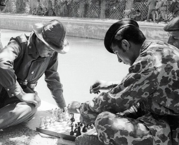 Soldații unui contingent limitat de trupe sovietice din Afganistan au sosit la locația trupelor aeriene ale republicii afgane. Soldații din URSS și militarii afgani joacă șah.Fotografie de epocă. Republica Democrată Afganistan. Războiul afgan 1979-1989 - Sputnik Moldova-România