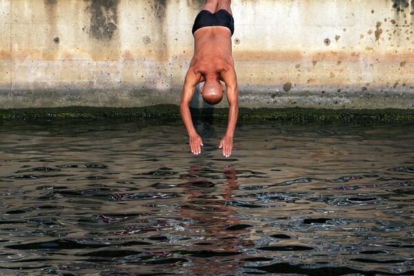 Мужчина ныряет в канал, чтобы освежиться после необычно жаркого дня в Пекине. - Sputnik Молдова