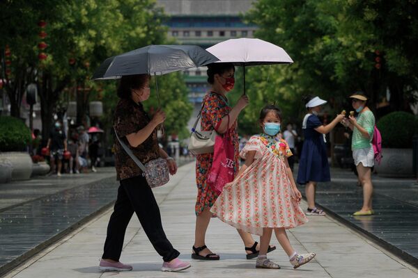 Женщины в масках держат зонтик во время прогулки по улице Цяньмэнь в Пекине. - Sputnik Молдова